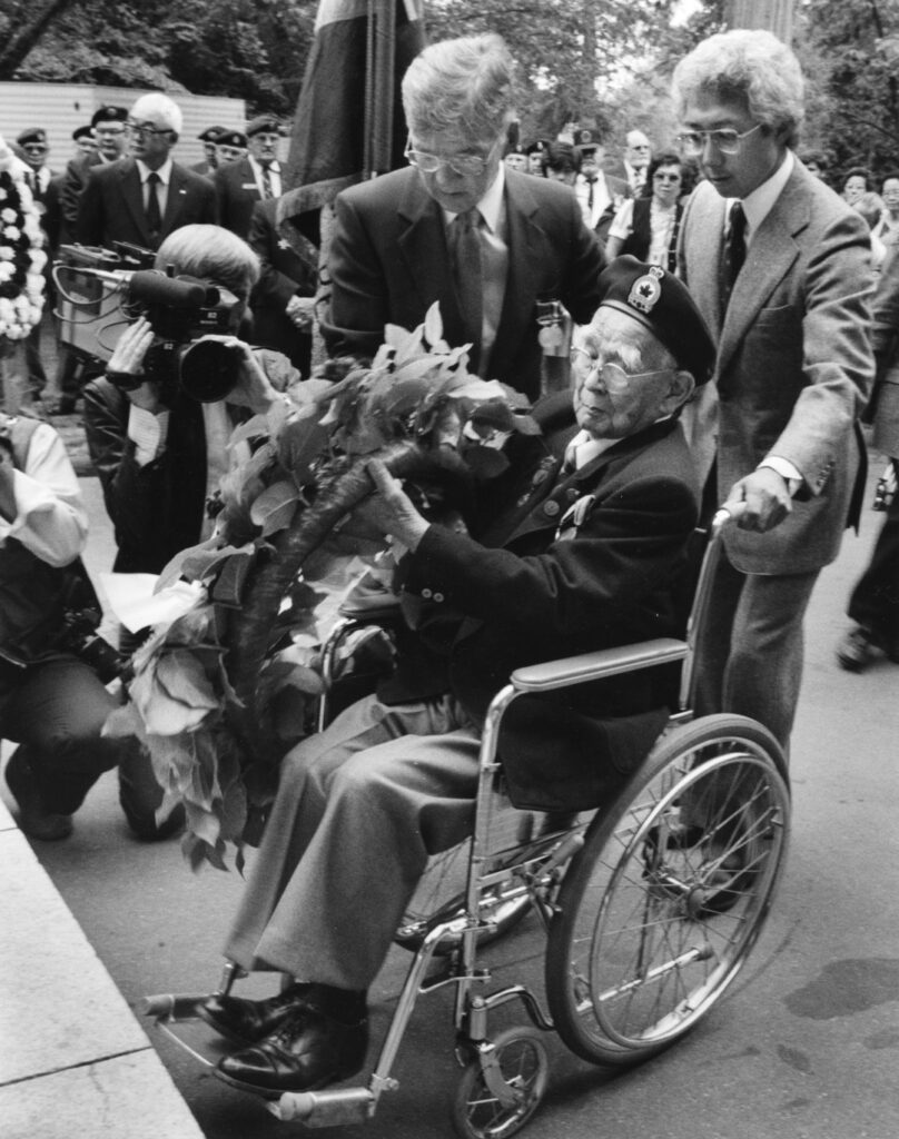 Sergeant Mitsui (seated, in wheelchair) placing a wreath at the Japanese Canadian War Memorial in Stanley Park, 1985. NNM 1992.23.
