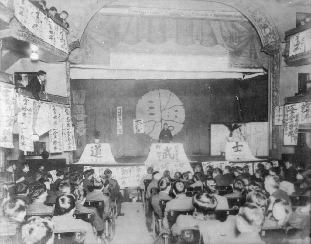 Community fundraising event, circa 1908. The Japanese characters on the panels at the front of the stage read "bushido", a word for the samurai code of values.